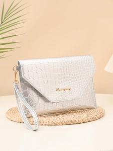 Macro detail of silver crocodile embossed leather clutch with gold metal logo and wristlet