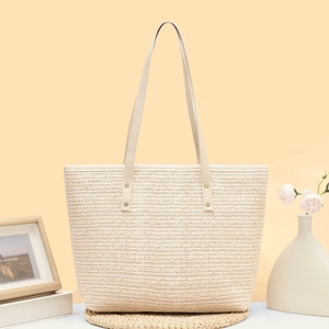 Minimalist woven straw tote bag with leather handles and metallic rivet details