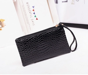 Detail of black crocodile texture wristlet pouch with golden zipper and leather strap