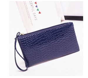 Detail of navy blue crocodile embossed leather wristlet bag with silver zipper closure
