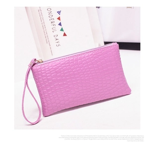 Detailed macro of pink crocodile pattern leather wristlet with golden zipper closure