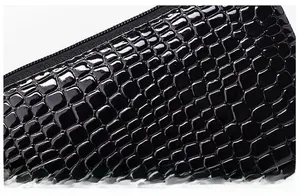 Close-up of black crocodile pattern imported leather with glossy finish and metal zipper
