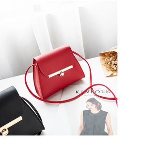 Detail of red and black mini crossbody bags with gold metal bar locks on a white desk