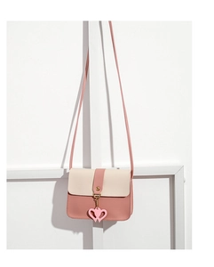 Detail of pink and beige mini square crossbody bag with heart charm and shoulder strap