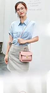 Close-up of elegant pale pink mini square bag with golden lock on a female model