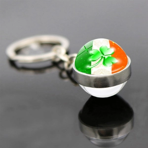 Macro view of Ireland flag glass dome keychain with green clover on reflective surface