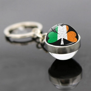 Macro view of double-sided glass keychain with Irish flag clover pattern on black background