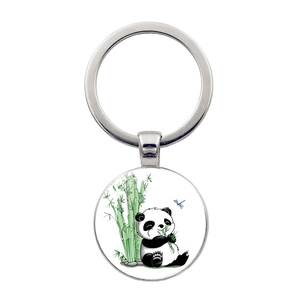 Close-up of a round metal keychain featuring a cute panda eating bamboo illustration