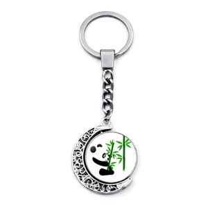 Porte-clés panda rotatif en forme de lune argentée avec motif bambou sur fond blanc