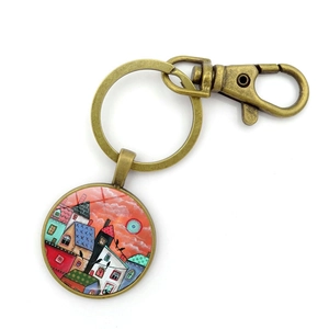 Détail d'un porte-clés en bronze vieilli avec pendentif rond illustré d'une maison colorée