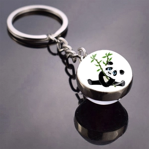 Detail of a polished metal keychain with a cute panda eating bamboo in a glass cabochon