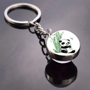 Close-up of a panda eating bamboo illustration in a round glass dome keychain pendant