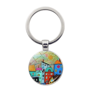 Detail of artistic round keychain featuring a colorful fairy tale house illustration