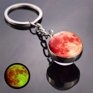 Detail of glow-in-the-dark moon keychain showing double-sided lunar texture and neon effect