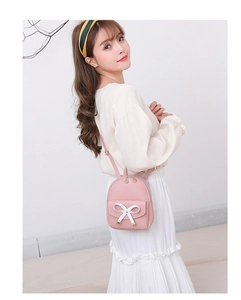 Detail of pink mini backpack with white bow decoration shown on model for casual styling