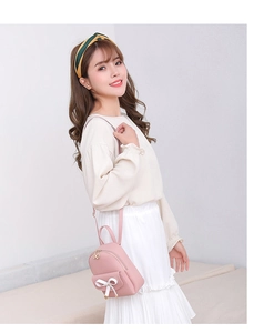 Detailed view of pink mini backpack with white bow decoration and gold zippers
