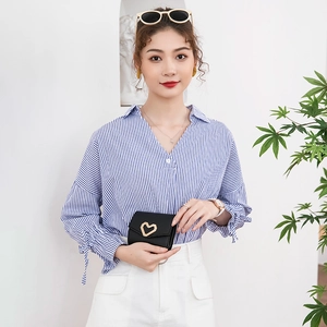 Portefeuille femme minimaliste en cuir noir avec fermoir coeur doré tenu par un modèle