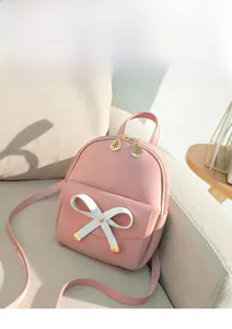 Detailed view of pink mini backpack with white bow decoration and gold leaf zipper pull