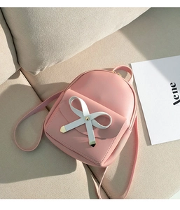 Close-up of pink mini backpack featuring a white bow detail and golden buckle accent
