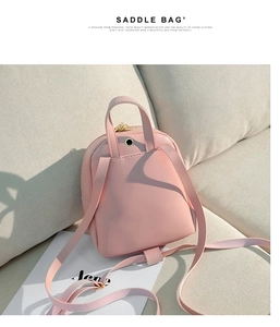 Pink mini leather backpack with bow detail and adjustable straps on fabric background