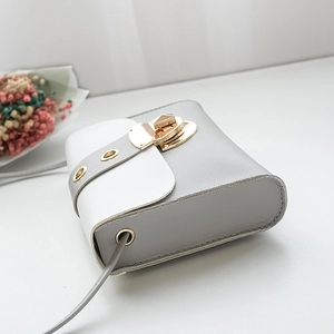 Sac bandoulière minimaliste bicolore avec fermoir doré sur fond blanc épuré