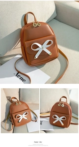 Detailed macro view of a mini brown leather backpack with a white bow and gold leaf zippers