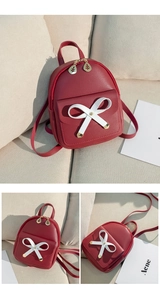 Detail view of mini wine red leather backpack with white bow and gold leaf zippers