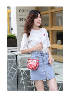 Détail du sac transparent rouge aux motifs marguerites blanches avec poignées dorées
