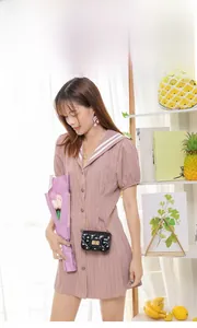 Close-up of black quilted mini bag with gold chain strap worn on pink dress