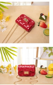 Detail view of red quilted jelly bag with gold chain and twist lock on a wooden desk