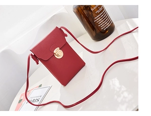 Détail du sac à téléphone rouge en cuir grainé avec une boucle en métal doré élégante