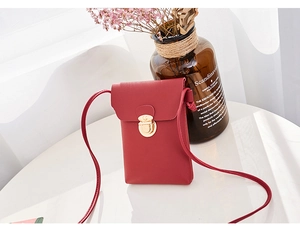 Détail d'un petit sac à bandoulière rouge mat pour téléphone avec boucle en métal doré
