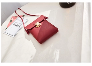 Détail du petit sac à bandoulière rouge pour téléphone avec boucle ronde dorée en métal