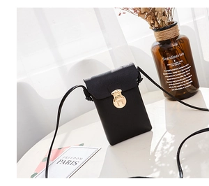 Détail de la pochette téléphone en cuir noir à grain de litchi et fermoir doré rond