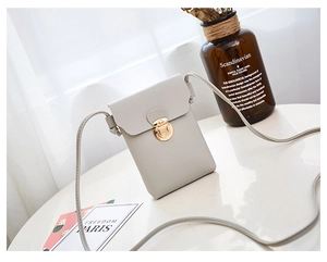 Détail du petit sac bandoulière en cuir gris clair avec fermoir en métal doré rond