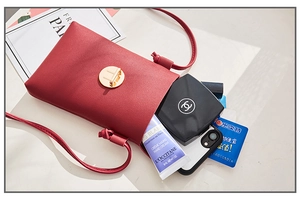 Vue détaillée du sac à bandoulière en cuir rouge avec cosmétiques et smartphone