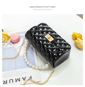 Detail of black quilted jelly bag with large pearl handle and golden twist lock closure
