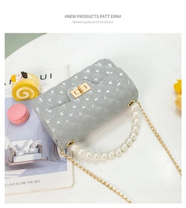 Detail of grey quilted jelly bag with pearl handle and gold chain on a styled table