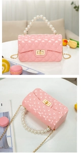Detailed macro view of pink quilted jelly bag with pearl handle and golden chain strap