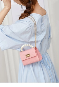 Pink crocodile-embossed mini jelly bag with pearl handle shown on model's outfit
