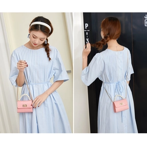 Pink croc-effect mini jelly bag with pearl handle and gold chain on a blue dress