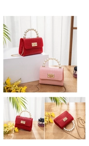 Detail of mini crocodile embossed jelly bag with pearl handle and golden twist lock