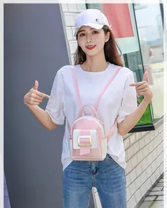Mini sac à dos contrasté rose et blanc avec boucle dorée élégante, porté à l'extérieur
