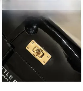 Detail of glossy black patent leather bag with premium gold metal twist lock hardware