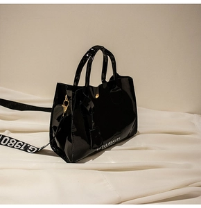 Détail du sac seau en cuir verni noir avec imprimé LITTLE BEAUTY et large bandoulière