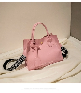 Détail du sac à main en cuir verni rose brillant avec bandoulière et logo