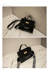 Detail of black patent leather handbag with gold twist lock and woven shoulder strap