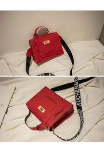 Detail view of mini red glossy patent leather Kelly bag with golden rotary lock and strap