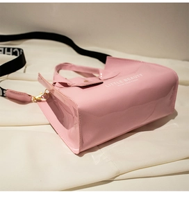Détail du mini sac en cuir verni rose avec lettrage blanc et bandoulière tissée