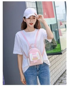 Photo en extérieur d'un mini sac à dos rose et blanc avec boucle dorée sur tenue